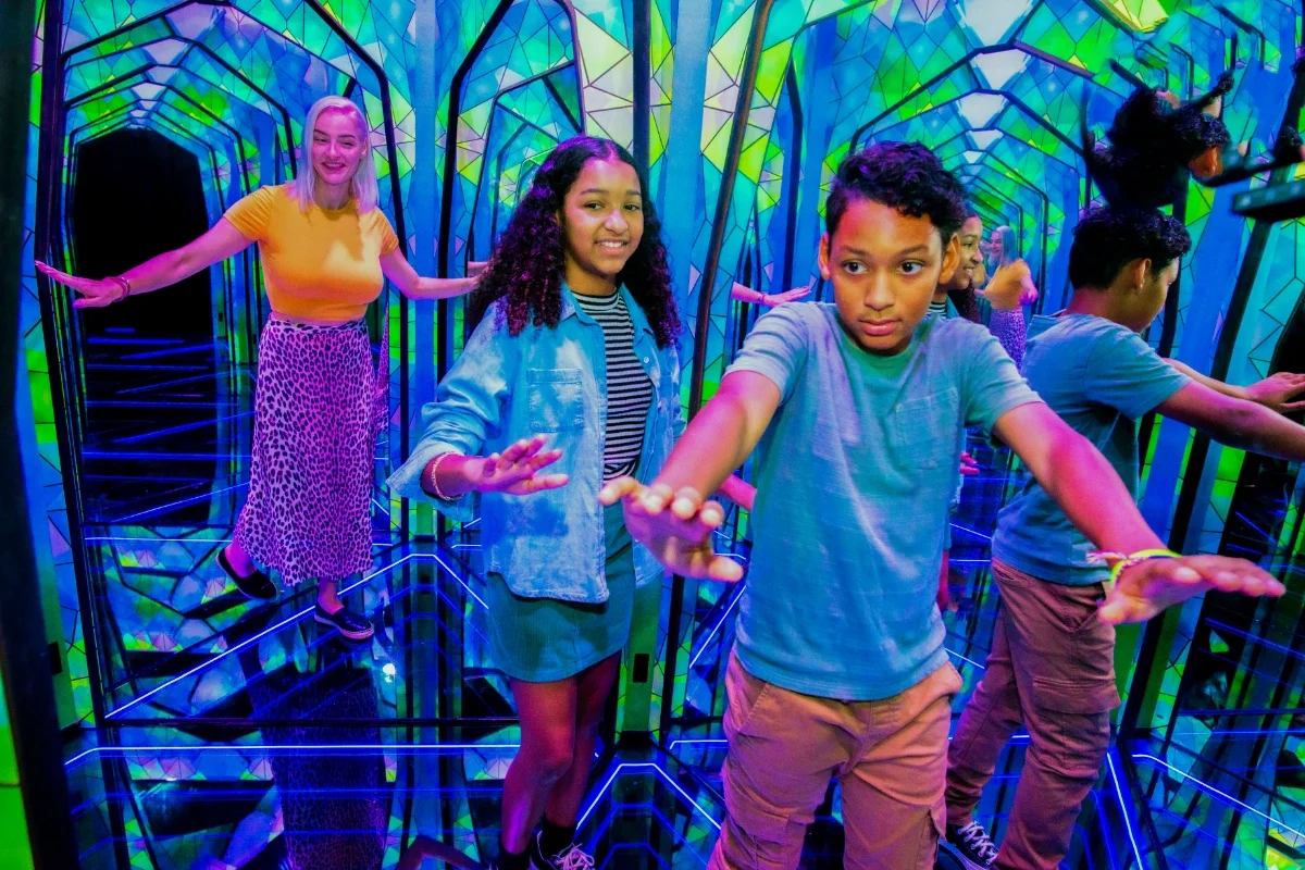 3 people in a colorful mirror maze