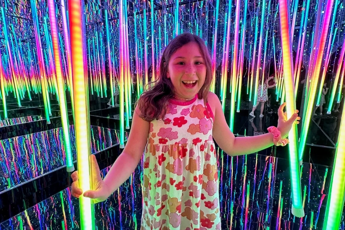 child smiling in a glow light mirror maze