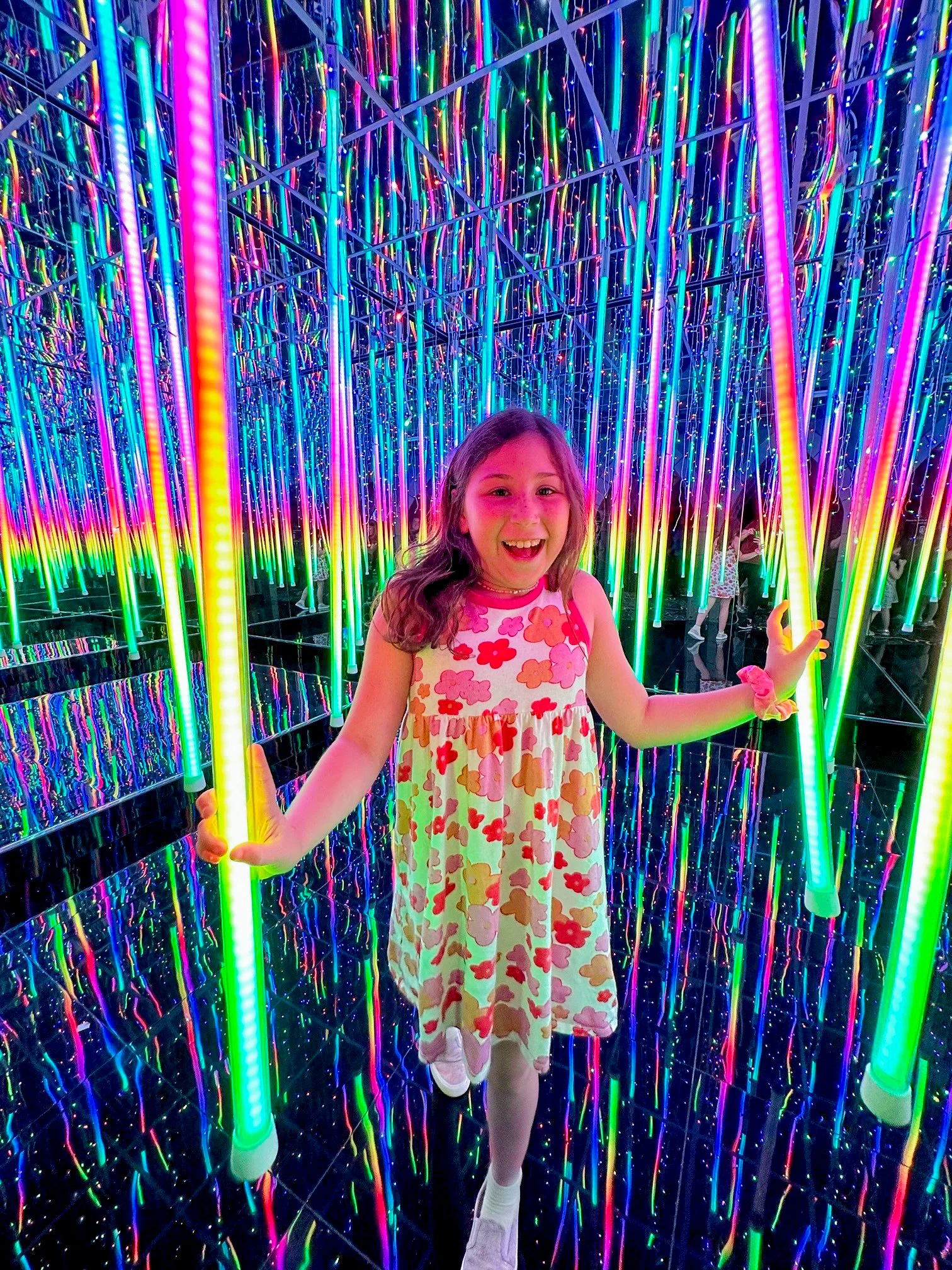 child smiling in a glow light mirror maze